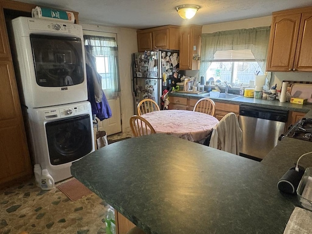 kitchen with stainless steel dishwasher, refrigerator, stacked washing maching and dryer, and sink