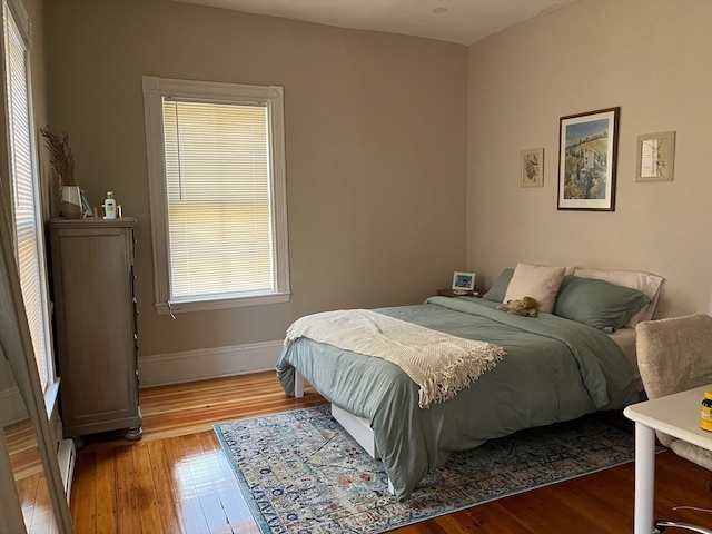 bedroom with baseboard heating and hardwood / wood-style floors