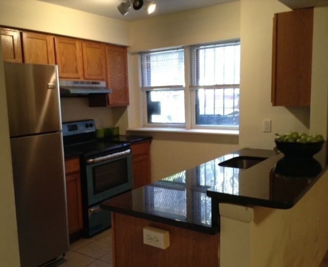 kitchen featuring kitchen peninsula, appliances with stainless steel finishes, a breakfast bar, and light tile patterned flooring