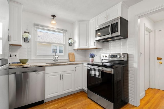 kitchen featuring stainless steel appliances, a sink, white cabinets, and light wood finished floors