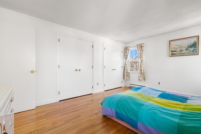 bedroom featuring light wood-type flooring, baseboard heating, and baseboards
