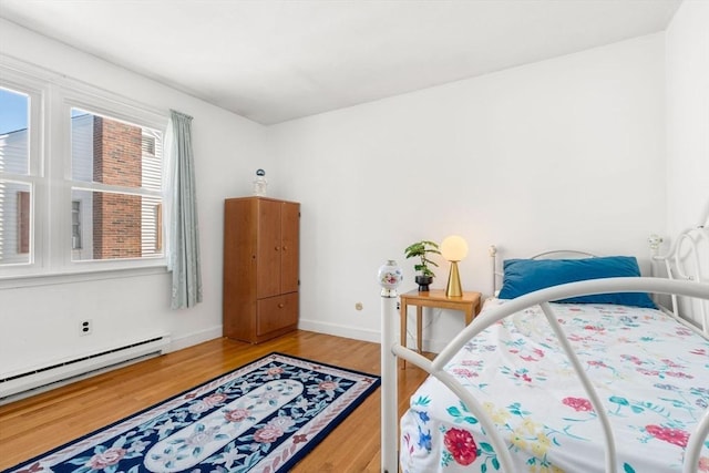bedroom featuring a baseboard radiator, light wood-type flooring, and baseboards
