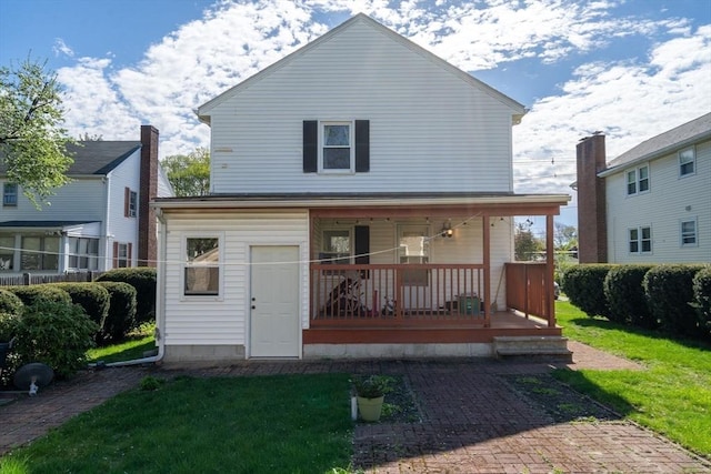 back of house with covered porch and a yard