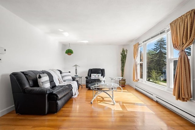 living room featuring a baseboard heating unit, light wood-style flooring, and baseboards