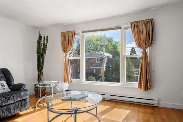 sitting room featuring a baseboard heating unit, wood finished floors, and baseboards