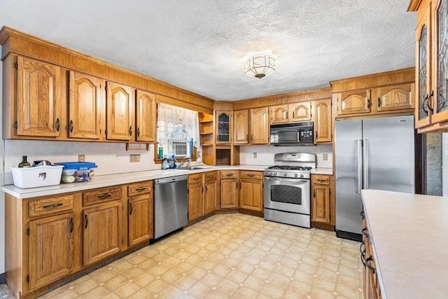 kitchen featuring light countertops, appliances with stainless steel finishes, brown cabinetry, and light floors