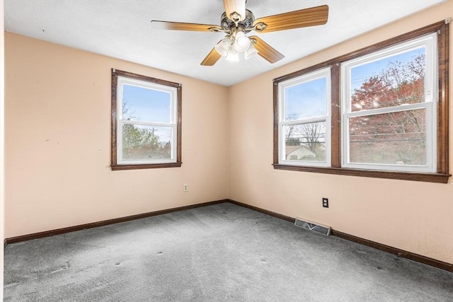 empty room with carpet, visible vents, a ceiling fan, and baseboards