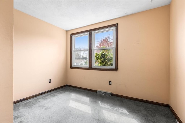 carpeted spare room with visible vents and baseboards