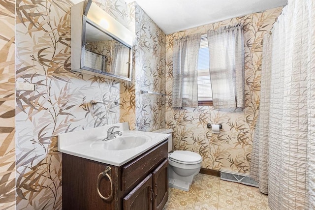 bathroom featuring toilet, visible vents, wallpapered walls, and vanity