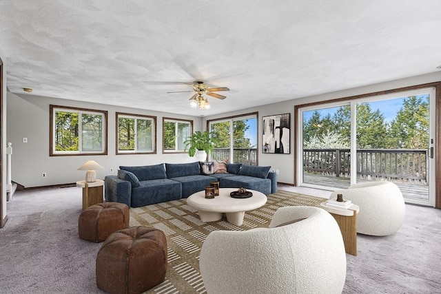 living area with baseboards, a ceiling fan, and light colored carpet