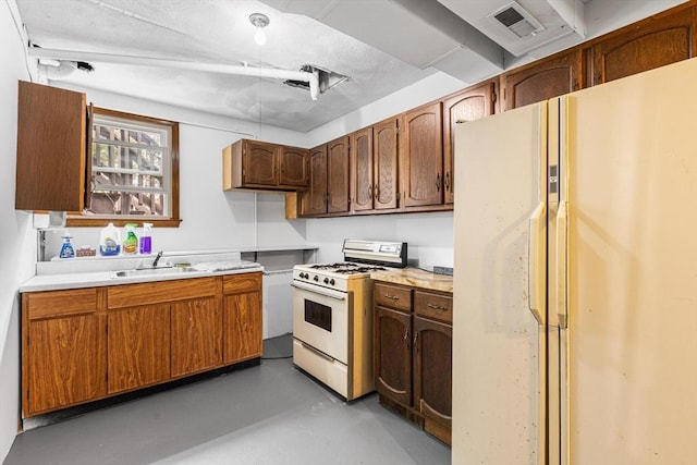 kitchen featuring a sink, white appliances, visible vents, light countertops, and finished concrete floors