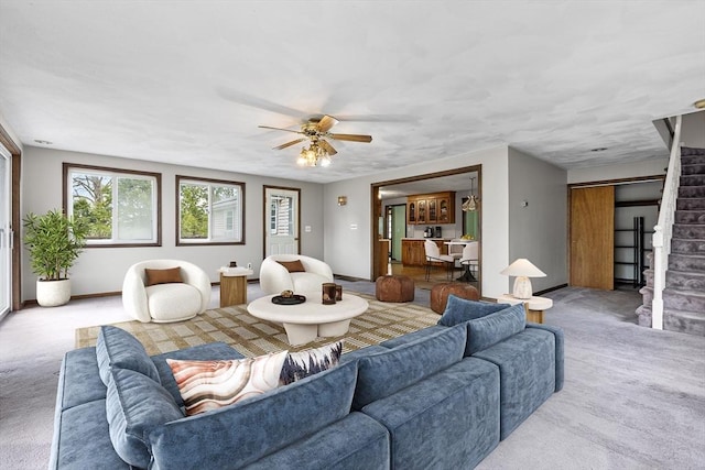 carpeted living room with ceiling fan, stairway, and baseboards