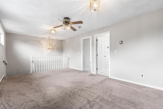 empty room featuring carpet, baseboards, and ceiling fan with notable chandelier