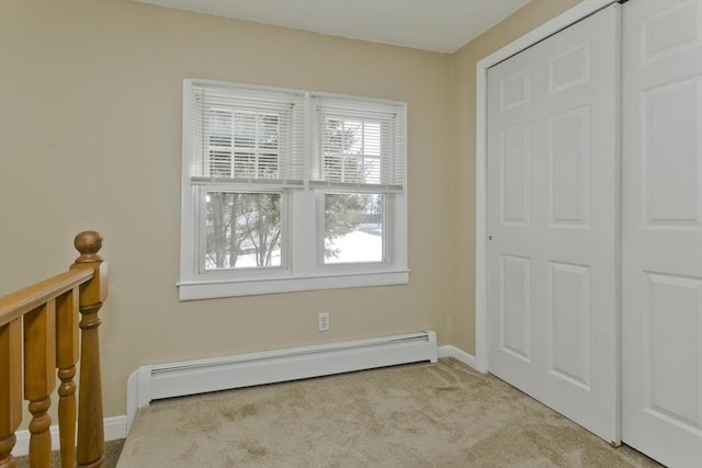 interior space featuring a baseboard heating unit, carpet floors, and baseboards