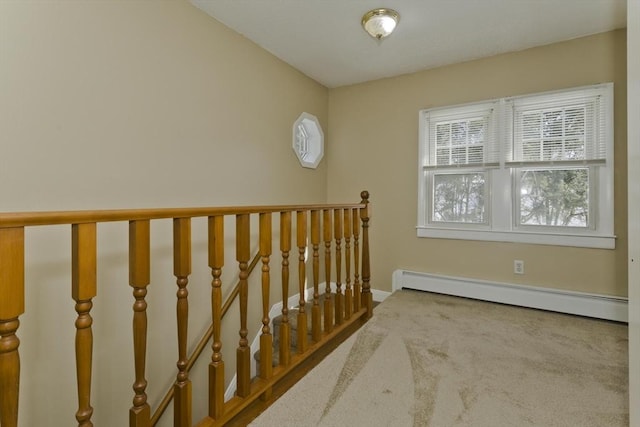 hallway with baseboard heating, carpet, an upstairs landing, and baseboards