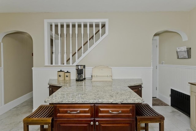 bar featuring radiator heating unit, arched walkways, and wainscoting