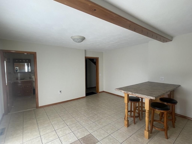 unfurnished dining area featuring beamed ceiling and light tile patterned floors