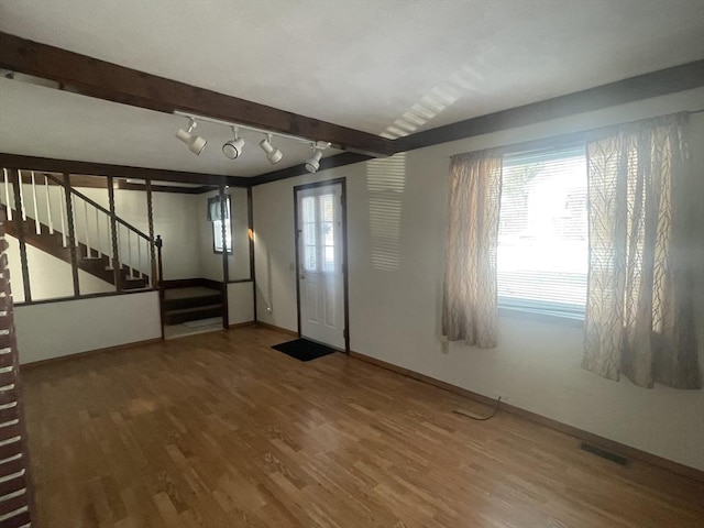 entryway featuring wood-type flooring, track lighting, beamed ceiling, and plenty of natural light