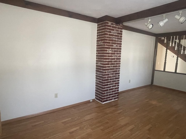 unfurnished living room with beamed ceiling, track lighting, and wood-type flooring