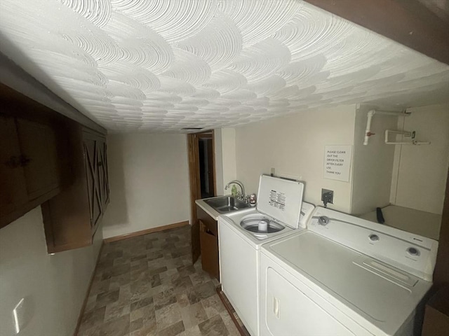 laundry area featuring cabinets, sink, washer and dryer, and a textured ceiling