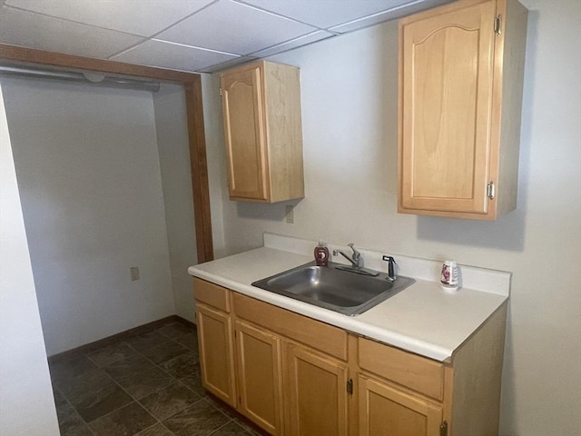 kitchen with light brown cabinetry, sink, and a paneled ceiling