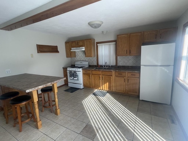 kitchen featuring tasteful backsplash, white appliances, sink, and light tile patterned floors