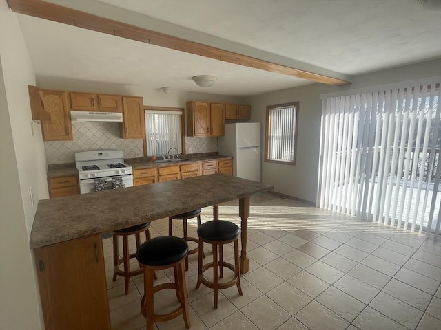 kitchen with tasteful backsplash, a wealth of natural light, a breakfast bar area, and white appliances