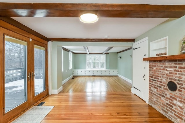 unfurnished living room featuring french doors, beam ceiling, and light wood-type flooring