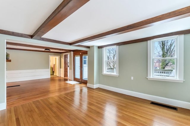 empty room featuring french doors, beam ceiling, and light hardwood / wood-style floors