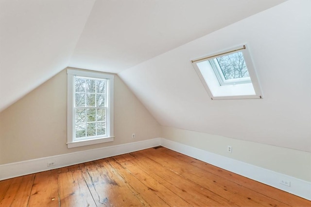 additional living space featuring lofted ceiling with skylight and hardwood / wood-style floors