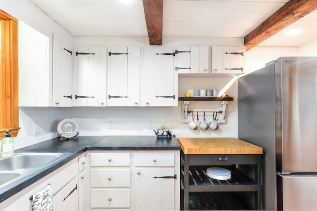 kitchen featuring white cabinets, stainless steel fridge, and beamed ceiling