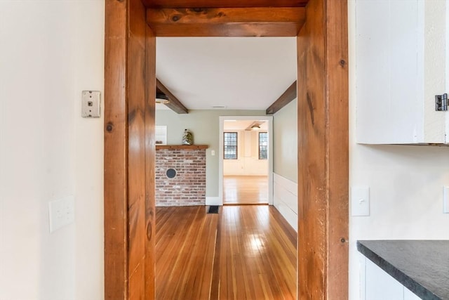 hallway with beamed ceiling and light hardwood / wood-style flooring