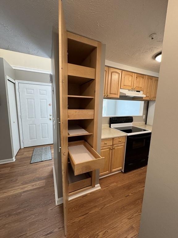 kitchen featuring dark wood-type flooring, light countertops, electric stove, under cabinet range hood, and a textured ceiling