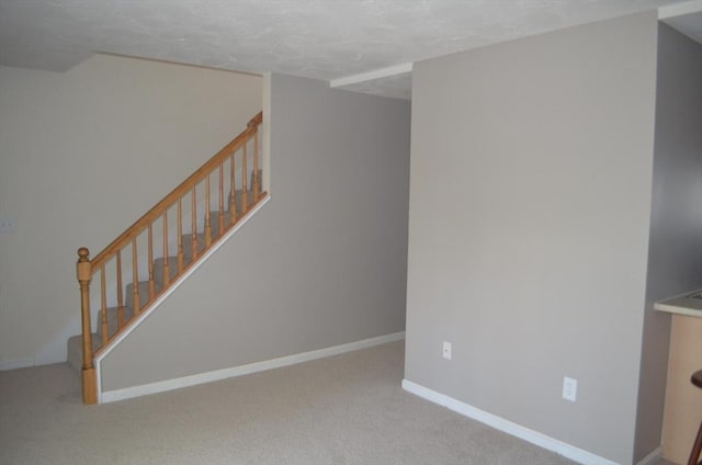 interior space featuring a textured ceiling, baseboards, and carpet floors