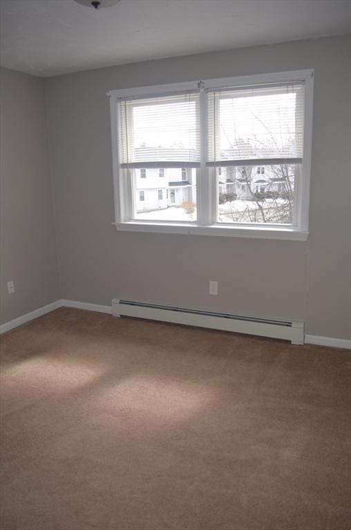 empty room featuring a baseboard heating unit, carpet floors, and baseboards