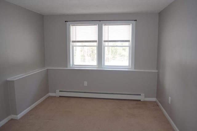 unfurnished room with a baseboard heating unit, light colored carpet, and baseboards