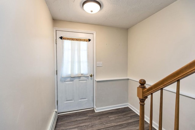 doorway featuring dark wood-type flooring, baseboards, and a textured ceiling