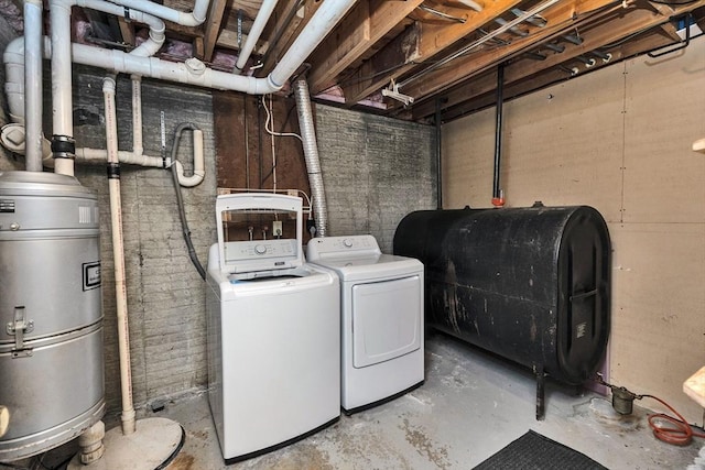 clothes washing area featuring laundry area, washing machine and dryer, and heating fuel