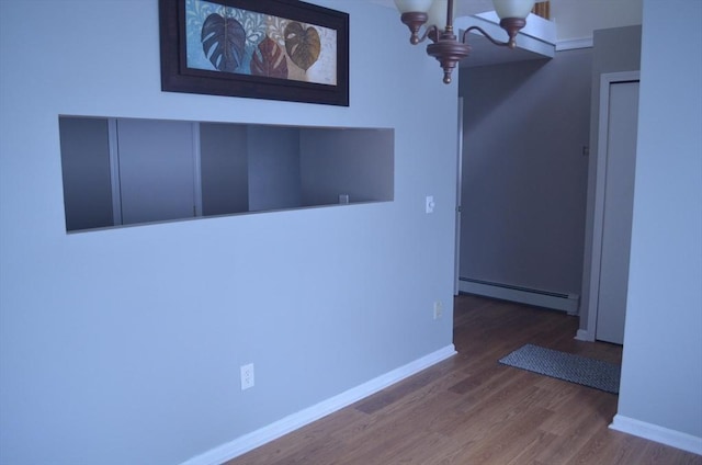 interior space with wood finished floors, baseboards, a chandelier, and a baseboard radiator