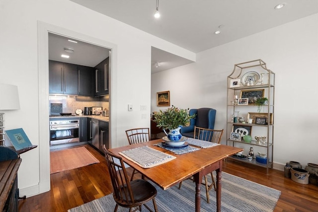 dining room with dark wood-type flooring, baseboards, and recessed lighting