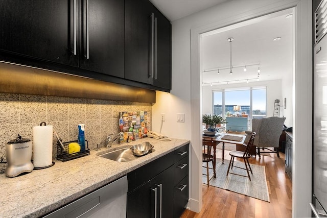 bar featuring a sink, tasteful backsplash, stainless steel dishwasher, and light wood-style floors