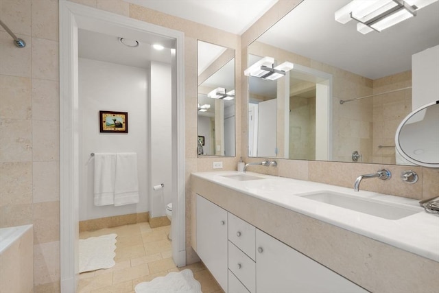 bathroom featuring tile patterned floors, tiled shower, a sink, and toilet