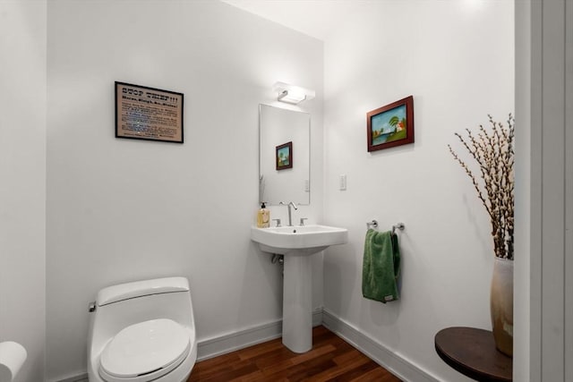 half bath featuring toilet, wood finished floors, and baseboards