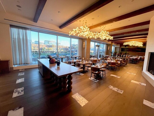 dining area featuring beamed ceiling, hardwood / wood-style floors, a notable chandelier, and a city view