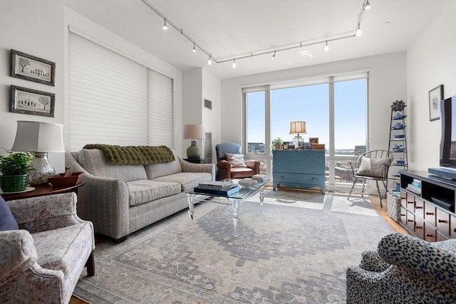 living area with rail lighting, visible vents, and wood finished floors