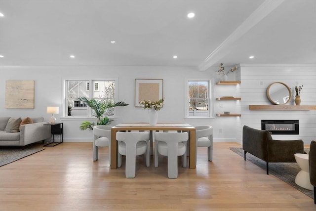 dining room with a wealth of natural light, a fireplace, and light wood-style floors