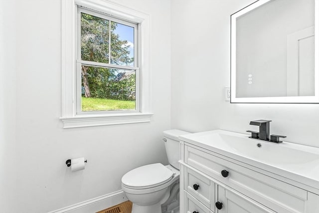 half bathroom with toilet, vanity, and baseboards