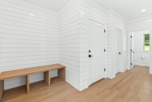 mudroom with light wood-style floors and wood walls