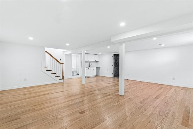 finished below grade area featuring recessed lighting, baseboards, stairs, and light wood finished floors