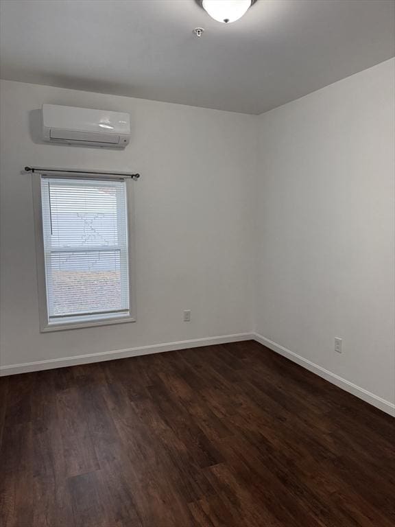 spare room with an AC wall unit and dark wood-type flooring